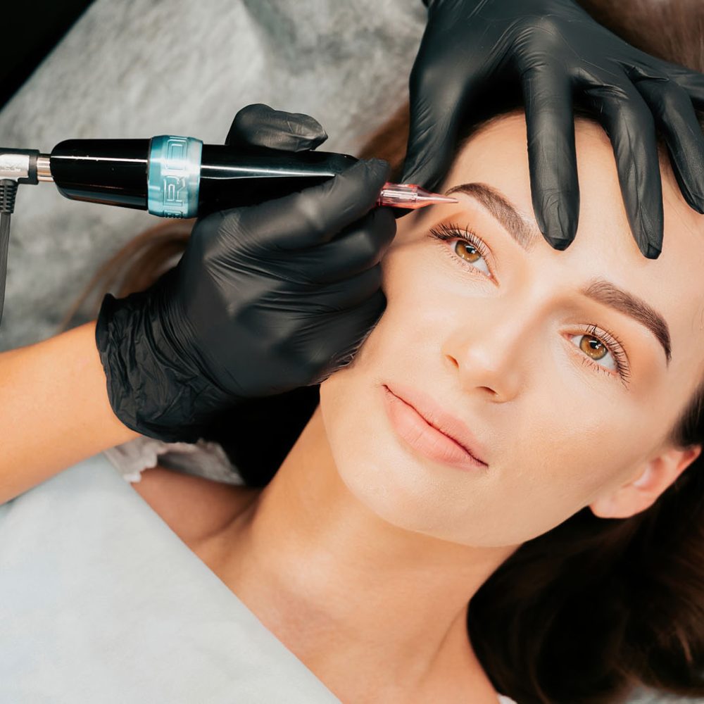 Make-up master performs the procedure of permanent eyebrow makeup for the client