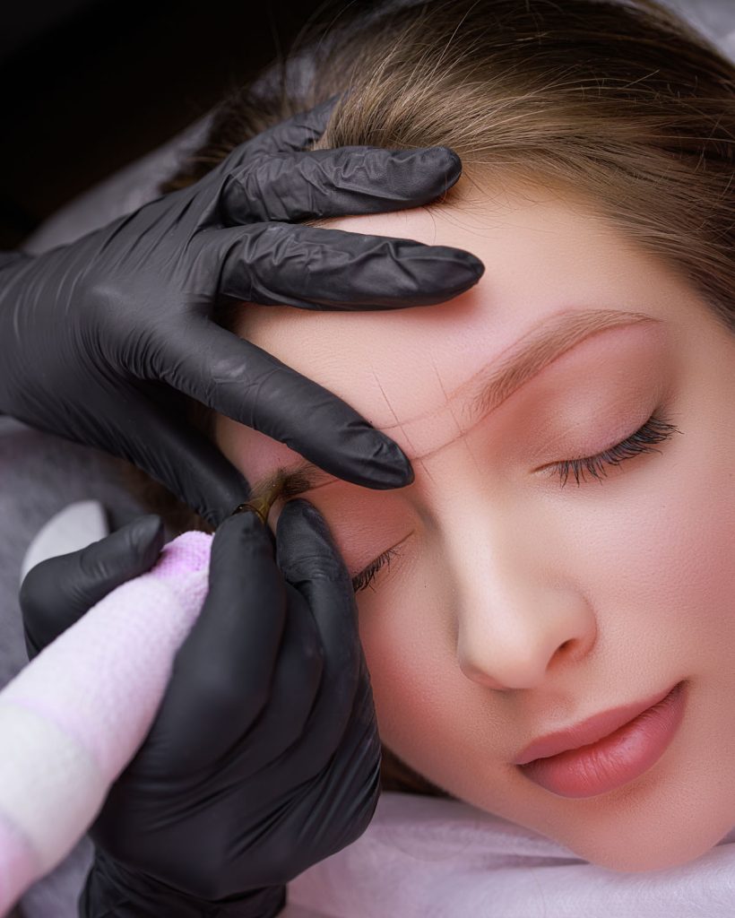 Master's hands close-up of permanent eyebrow makeup. PMU Procedure, Permanent Eyebrow Makeup.